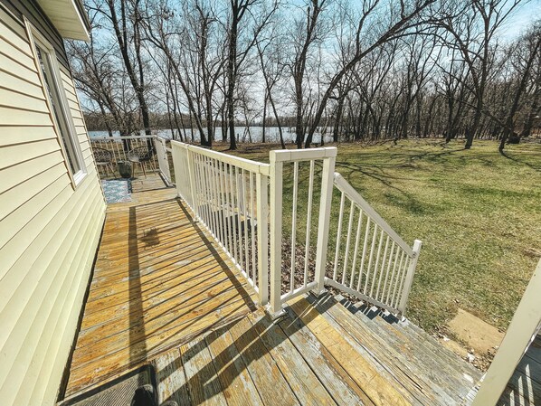 Une terrasse en bois avec une balustrade blanche menant à une maison dotée d’une fenêtre.
