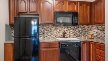 A kitchen with wooden cabinets, a stainless steel refrigerator, a microwave, and a dishwasher.