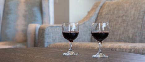 Two wine glasses on a wooden table with a sofa in the background.