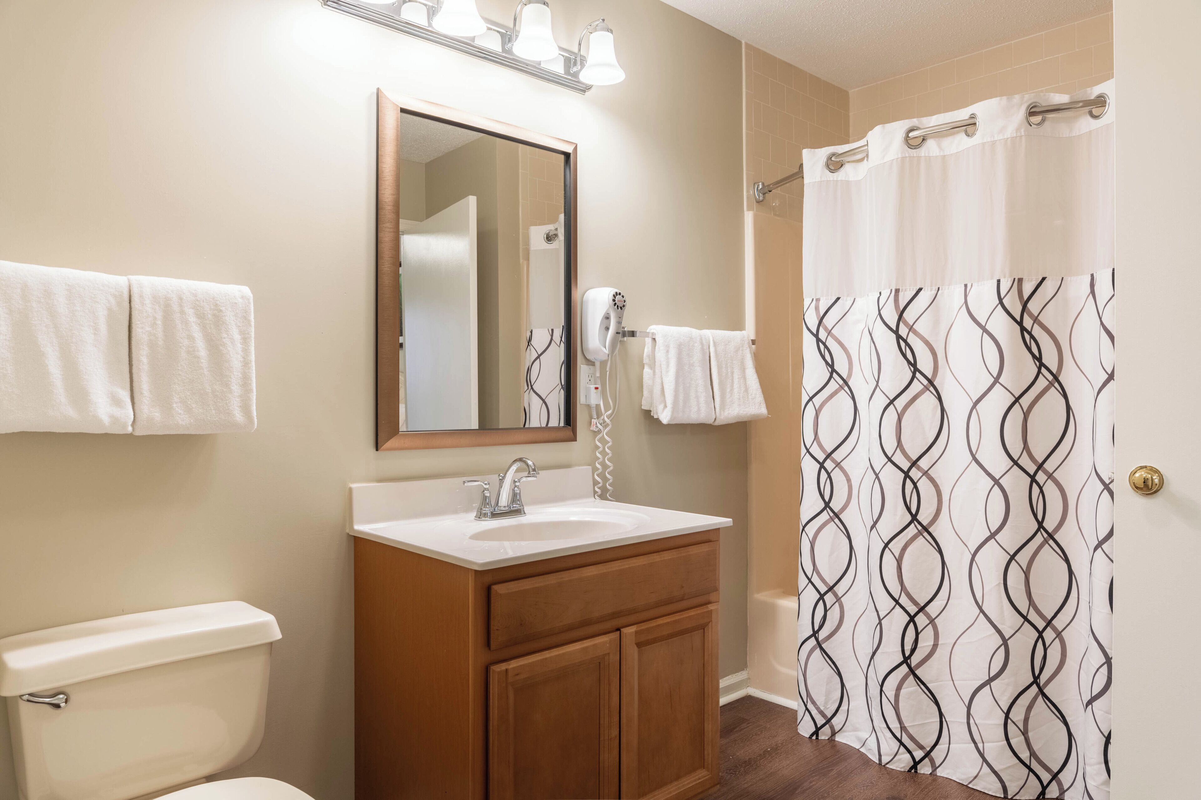 A bathroom with a sink, mirror, towel rack, and shower curtain.