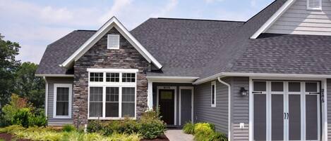 A modern two-story house with a stone facade, a large front window, and a garage.