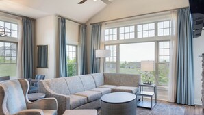 A modern living room with a sectional sofa, a round coffee table, and a side table with a lamp. - Massanutten Resort (McGaheysville)