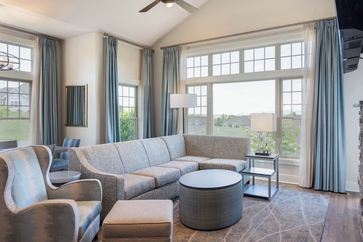 A modern living room with a sectional sofa, a round coffee table, and a side table with a lamp.