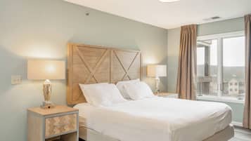 Una habitación de hotel con cama, dos lámparas de noche, una mesita de noche con lámpara y una ventana con cortinas.
