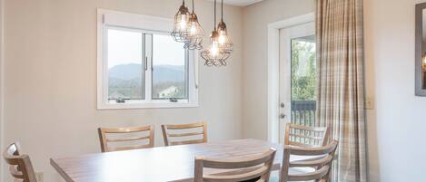 Comedor con mesa de madera, cuatro sillas y vista por una ventana.