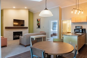 A modern kitchen with a microwave, a dining area with a round table and chairs, a fireplace, and a television mounted on the wall. - Massanutten Resort (McGaheysville)