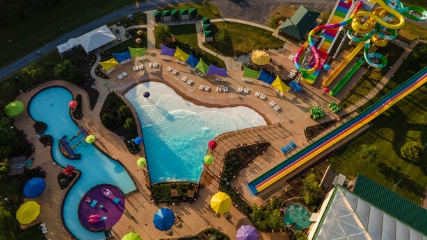 An aerial view of a water park with a large pool, multiple slides, and sun loungers. - Massanutten Resort (McGaheysville)