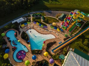 Vista aérea de un parque acuático con una piscina grande, varias toboganes y tumbonas.