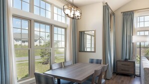 A dining area with a wooden table and chairs, large windows, a mirror, and a side table. - Massanutten Resort (McGaheysville)