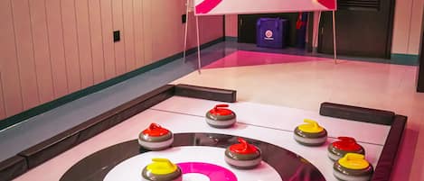 Pista de curling com pedras de curling dispostas em círculo, placar e faixa com a inscrição 'The Rink at Massanutten'.