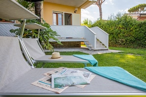 Un espacio al aire libre con sol, sillones de descanso, un sombrero y periódicos.