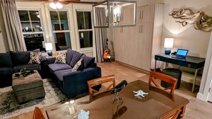 Un coin repas avec une table et des chaises en bois, un ventilateur de plafond et une guitare en arrière-plan.