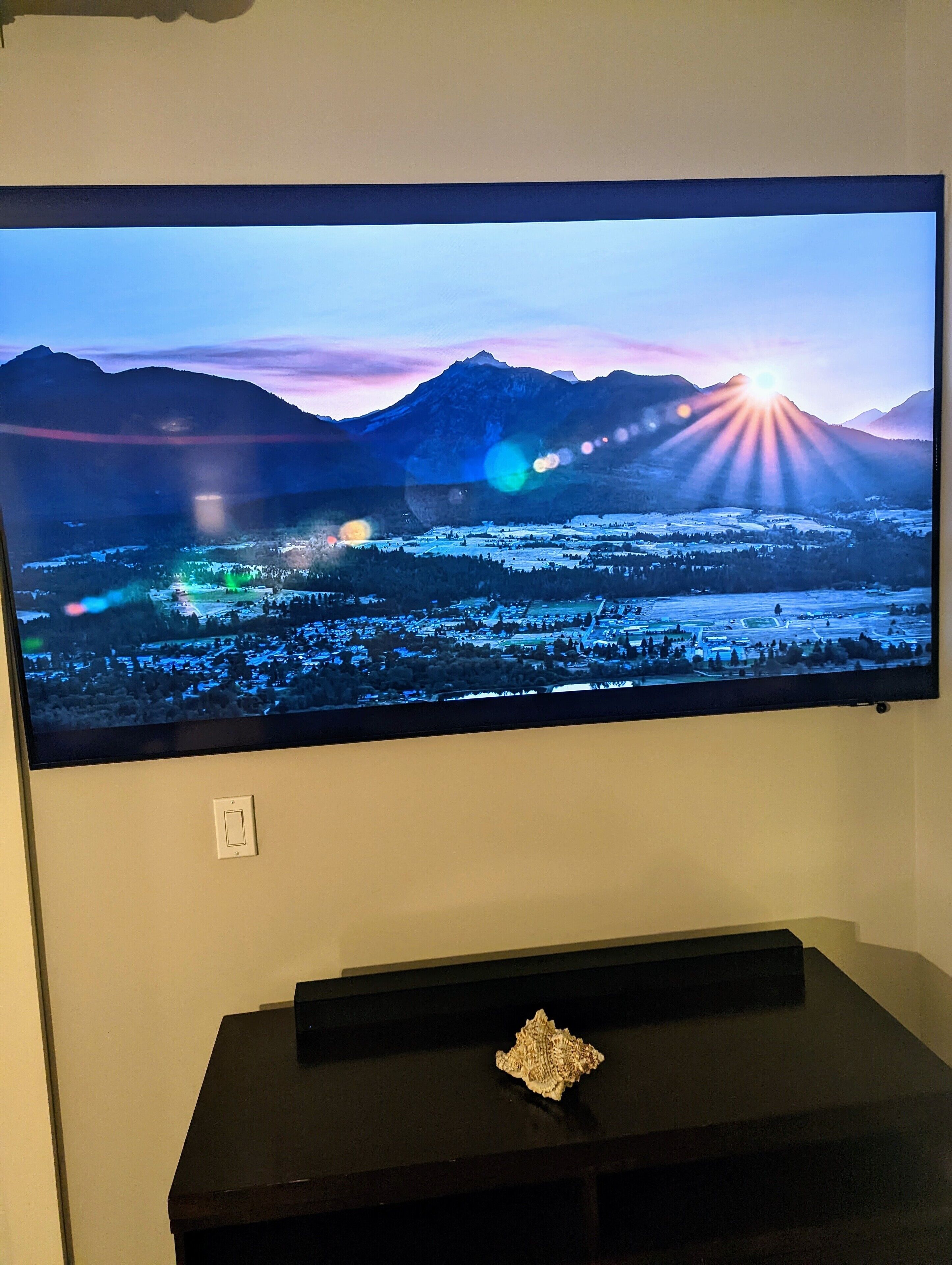 A flat-screen TV mounted on a wall displaying a scenic landscape.