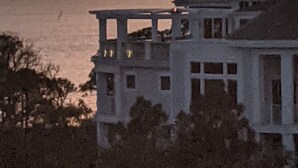 Une maison située sur la côte, dotée d’un balcon donnant sur la mer au coucher du soleil.
