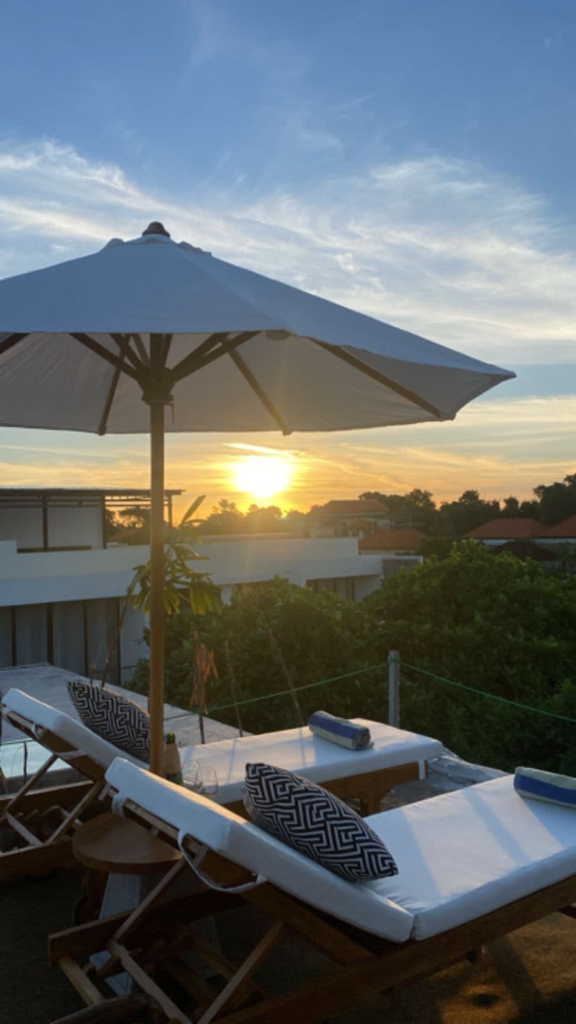 Une terrasse sur le toit, dotée de chaises longues et d’un parasol, offrant une vue imprenable sur le coucher du soleil.