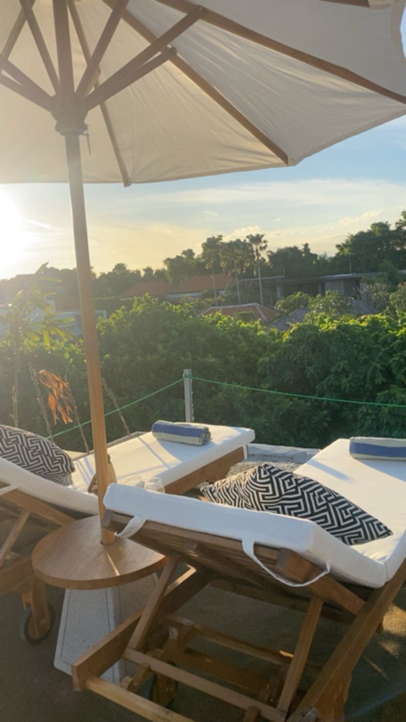 A rooftop terrace with lounge chairs, a table, and an umbrella.