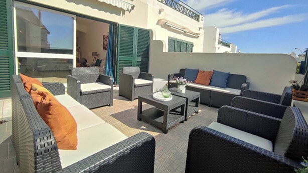 Eine Terrasse im Freien mit Korbmöbeln, einer Couch und einem Tisch.