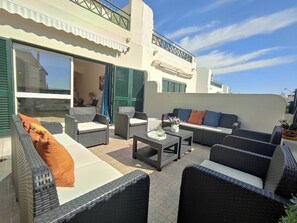 Un patio exterior con mobiliario de mimbre, un sofá y una mesa.