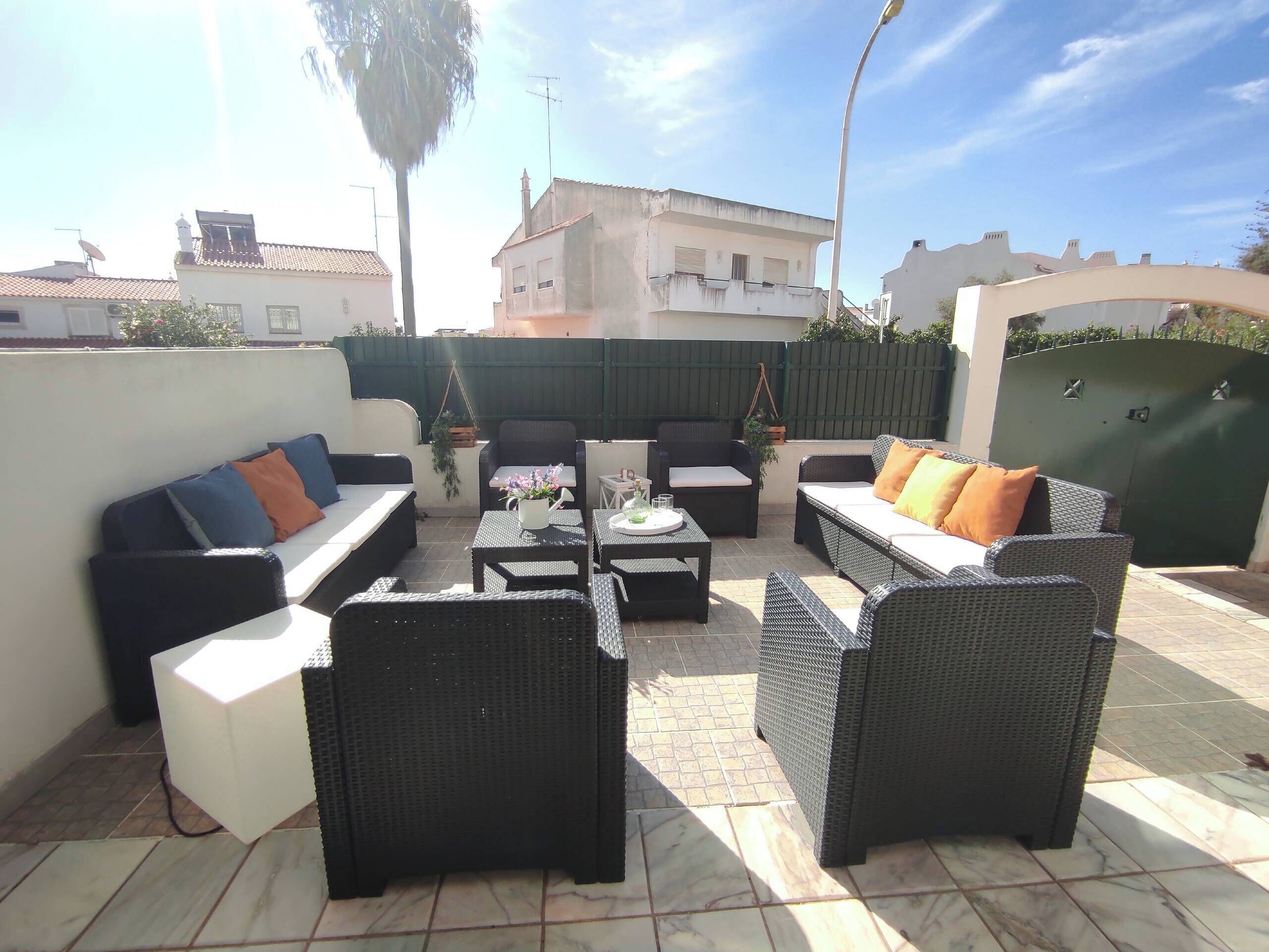 An outdoor patio with wicker furniture, a small table, and a hanging plant.