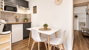 A compact kitchen with a microwave, coffee machine, and a small dining table with chairs.