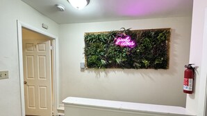 A hallway with a white door, a neon sign, a fire extinguisher, and a wall-mounted plant display. - Downtown Home - Close to Topgolf, Ravens Stadium, Orioles Park, UM Baltimore (Baltimore)