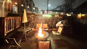 An outdoor patio with a fire pit, seating, and a stone wall. - Downtown Home - Close to Topgolf, Ravens Stadium, Orioles Park, UM Baltimore (Baltimore)