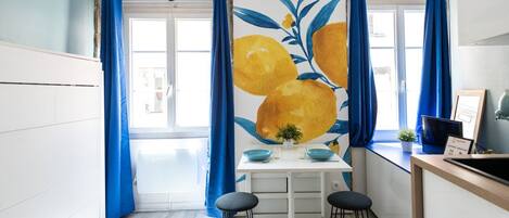 Una cocina moderna con encimera blanca, cortinas azules y un amplio ventanal.
