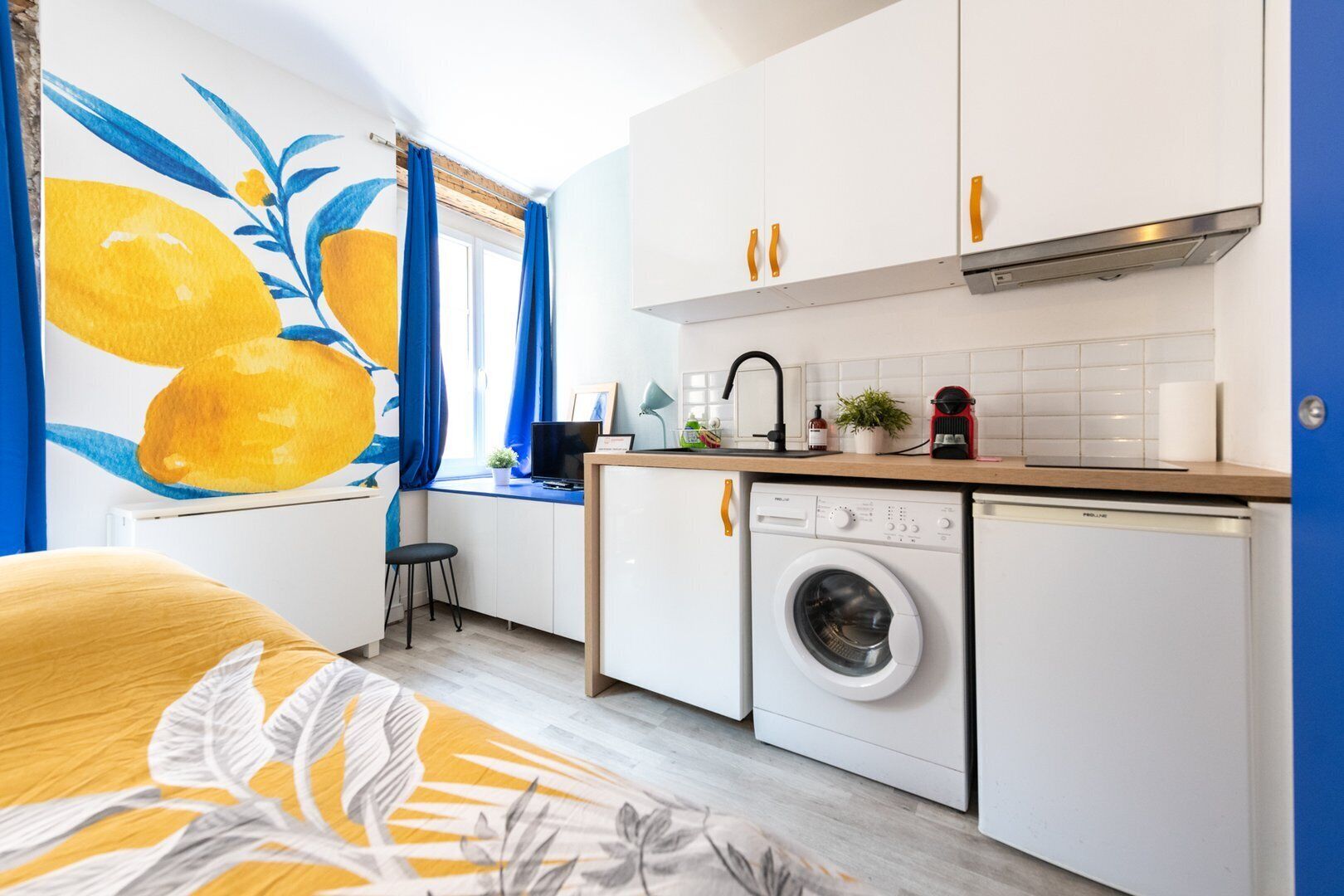 Cocina compacta con lavadora, lavamanos y encimera con varios objetos.