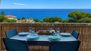 Un área de comedor al aire libre con una mesa dispuesta para cuatro personas, con vista al mar.