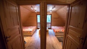 A wooden cabin with two bedrooms, each with a bed and a window.