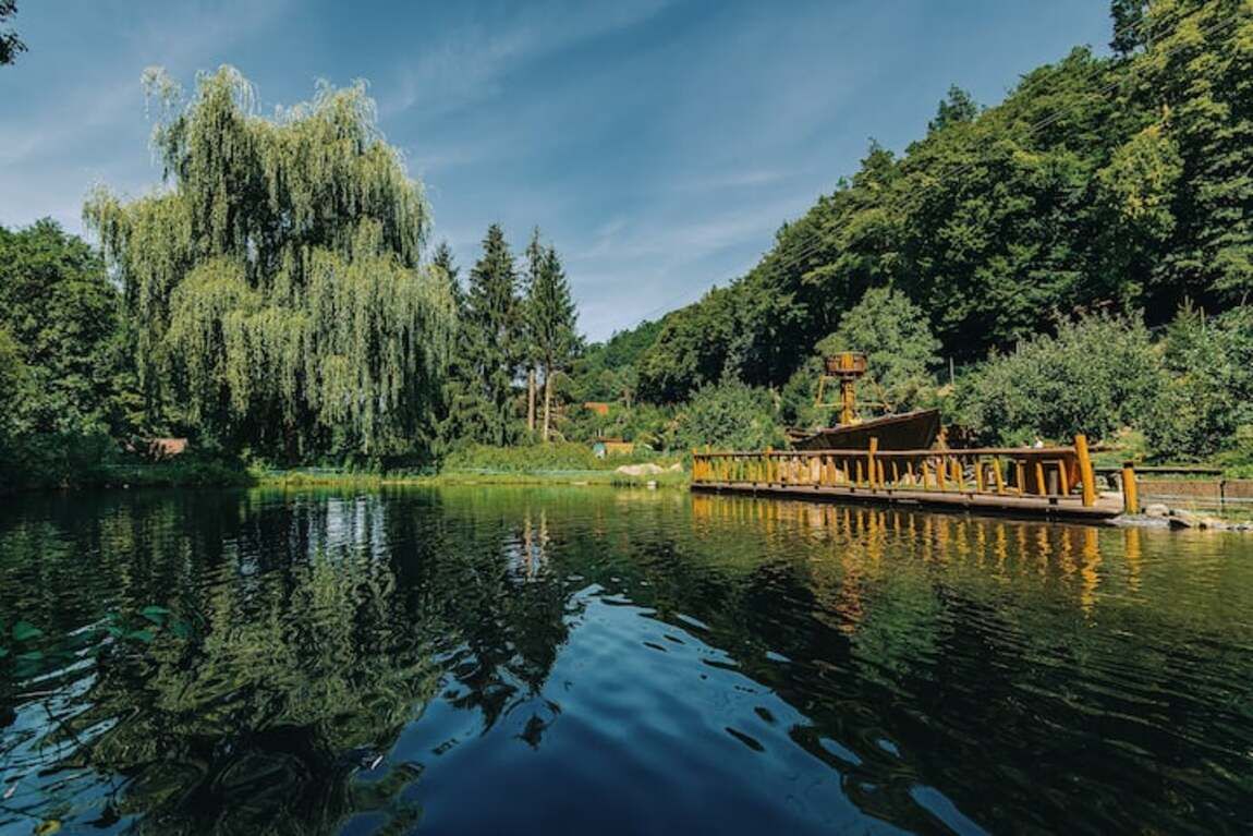 Eine friedliche Flusslandschaft mit einem hölzernen Bootssteg und üppigem Grün.