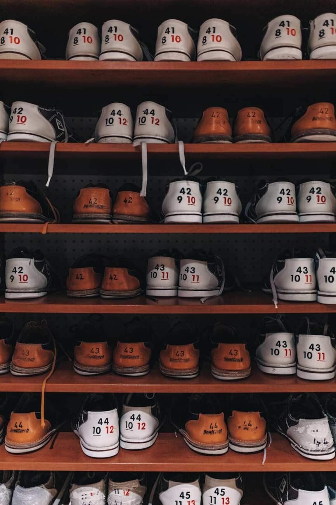 A shoe rack with multiple shelves containing pairs of shoes, each labeled with numbers.