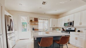Una cocina moderna con armarios blancos, electrodomésticos de acero inoxidable y una isla grande con taburetes de bar.