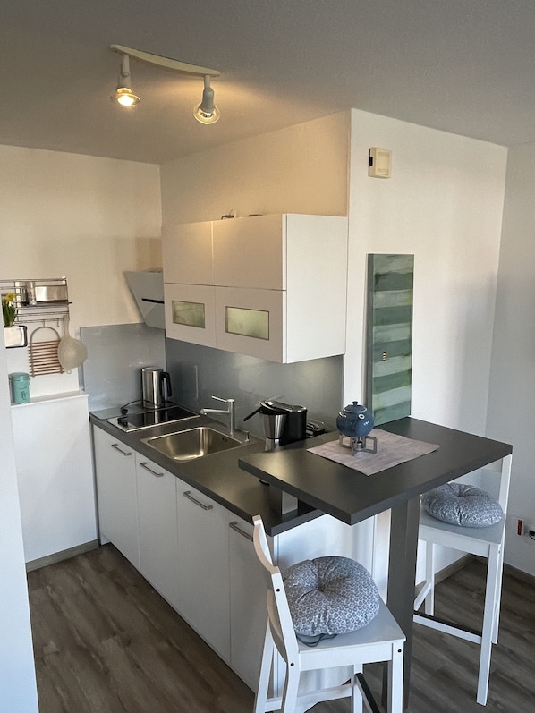Una cocina moderna con un lavabo doble, electrodomésticos de acero inoxidable y una pequeña isla con taburetes de bar.