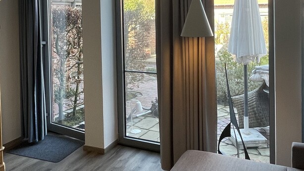 A hotel room with a large window, a bed, a chair, and a lamp.