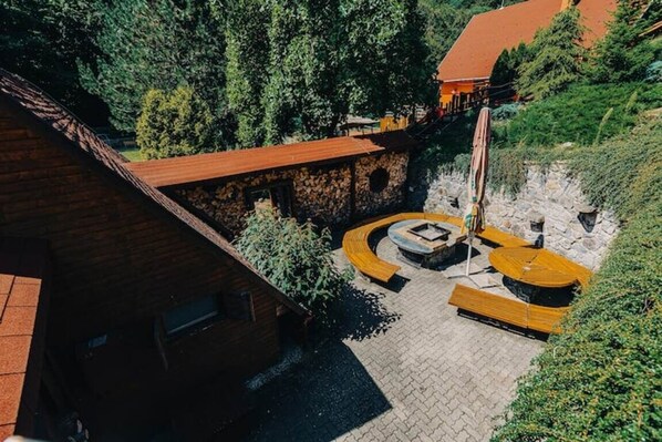 Ein Innenhof mit einer Steinmauer, einer hölzernen Bank und einer runden Sitzgruppe.