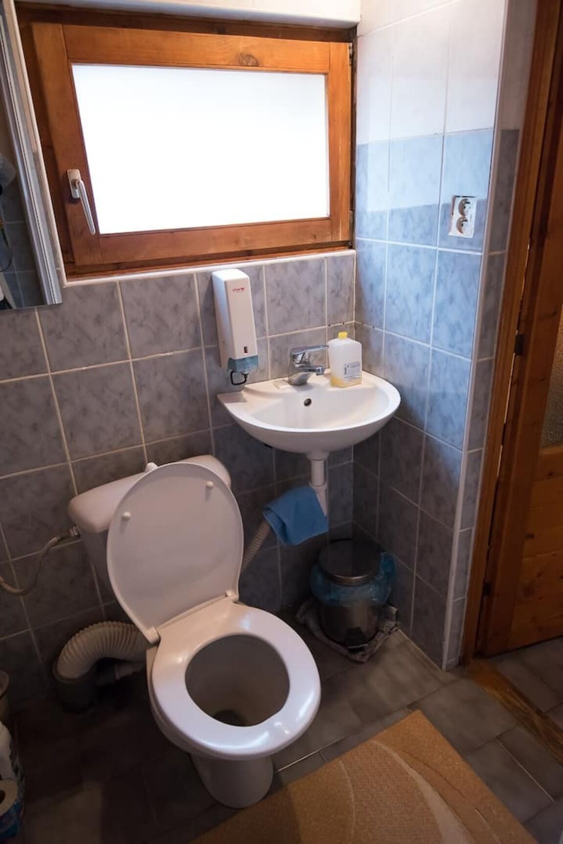 Une petite salle de bain avec des toilettes, un lavabo et une fenêtre.