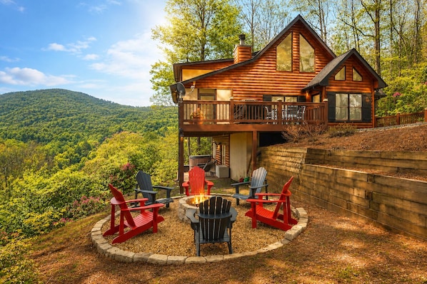 A log cabin with a deck, a fire pit, and outdoor seating.