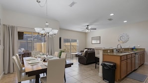 A spacious kitchen with a dining area, a ceiling fan, and a clock on the wall.