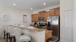 A modern kitchen with granite countertops, stainless steel appliances, and wooden cabinets.