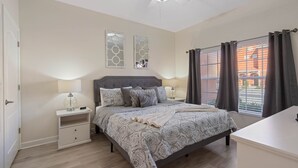 A bedroom with a bed, bedside tables, a ceiling fan, and a window with curtains.
