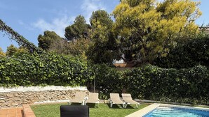 Un espace aménagé au bord de la piscine, avec des chaises longues et une table où sont servis des plats et des boissons.