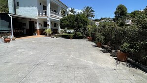 Une cour spacieuse avec une maison à deux étages, un patio couvert et des plantes en pot.