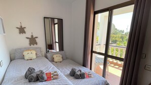 Une chambre avec deux lits, une grande fenêtre et un balcon.