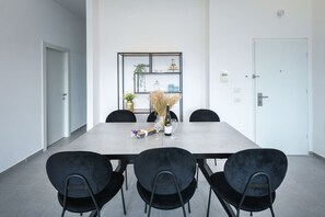 A conference room with a long table, four black chairs, a decorative wall shelf, and a white door.