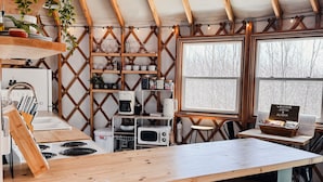 A cozy kitchen with a wooden island, bar stools, a stove, and a refrigerator. - Private Romantic Luxury Yurt- Sunset deck with Mt Views-Hot Tub-AC-WiFi-Fire Pit (Woodstock)