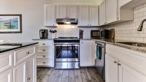 A modern kitchen with white cabinetry, stainless steel appliances, and a tiled backsplash.