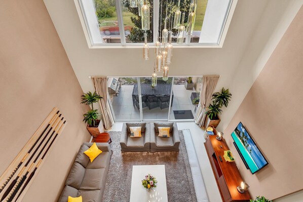 A spacious living area with a large window, a sofa, a coffee table, and a TV.