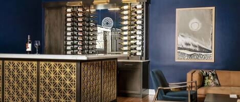 A bar area with a wine rack, a sofa, and a painting on the wall.