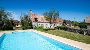 A swimming pool with a stone border, surrounded by a grassy lawn and a stone wall. - Longère classée 4 étoiles - piscine  – Ambillou (Ambillou)